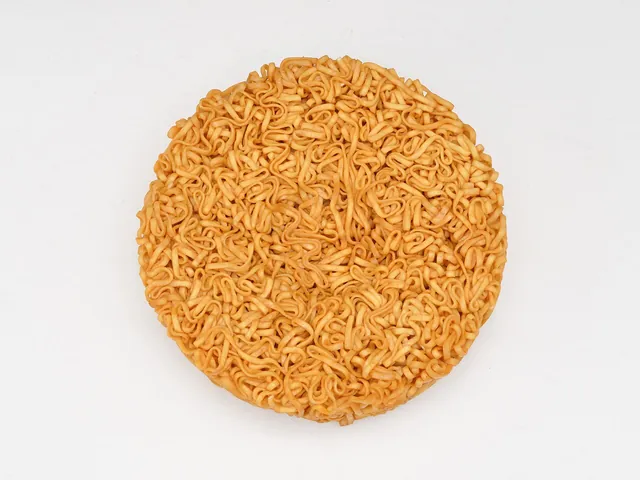 Nissin Chicken Ramen noodle block. An actual dried Chicken Ramen noodle block, photographed in 2022. This modern product photograph is not a record of the first 1958 release.