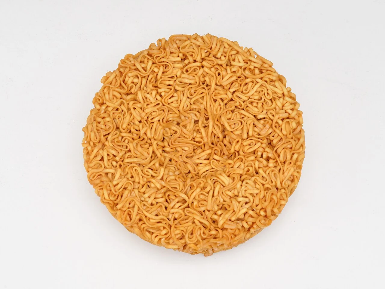 Nissin Chicken Ramen noodle block. An actual dried Chicken Ramen noodle block, photographed in 2022. This modern product photograph is not a record of the first 1958 release.