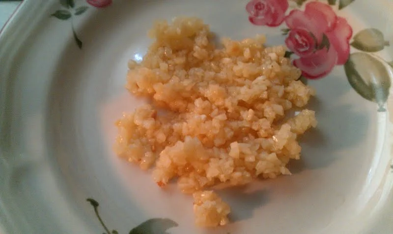 A small pile of minced garlic on a floral plate.