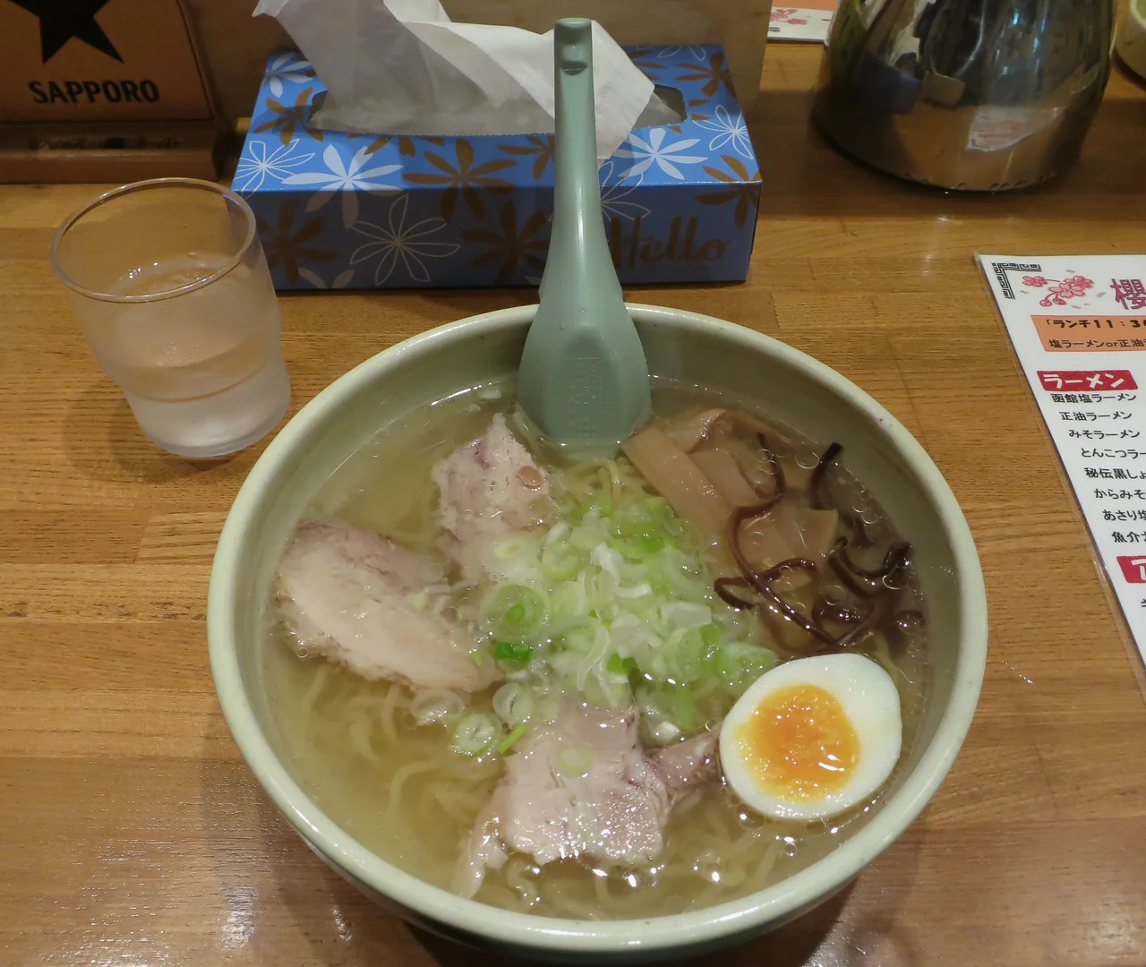 A bowl of shio ramen with pale broth, sliced pork, egg and scallions.