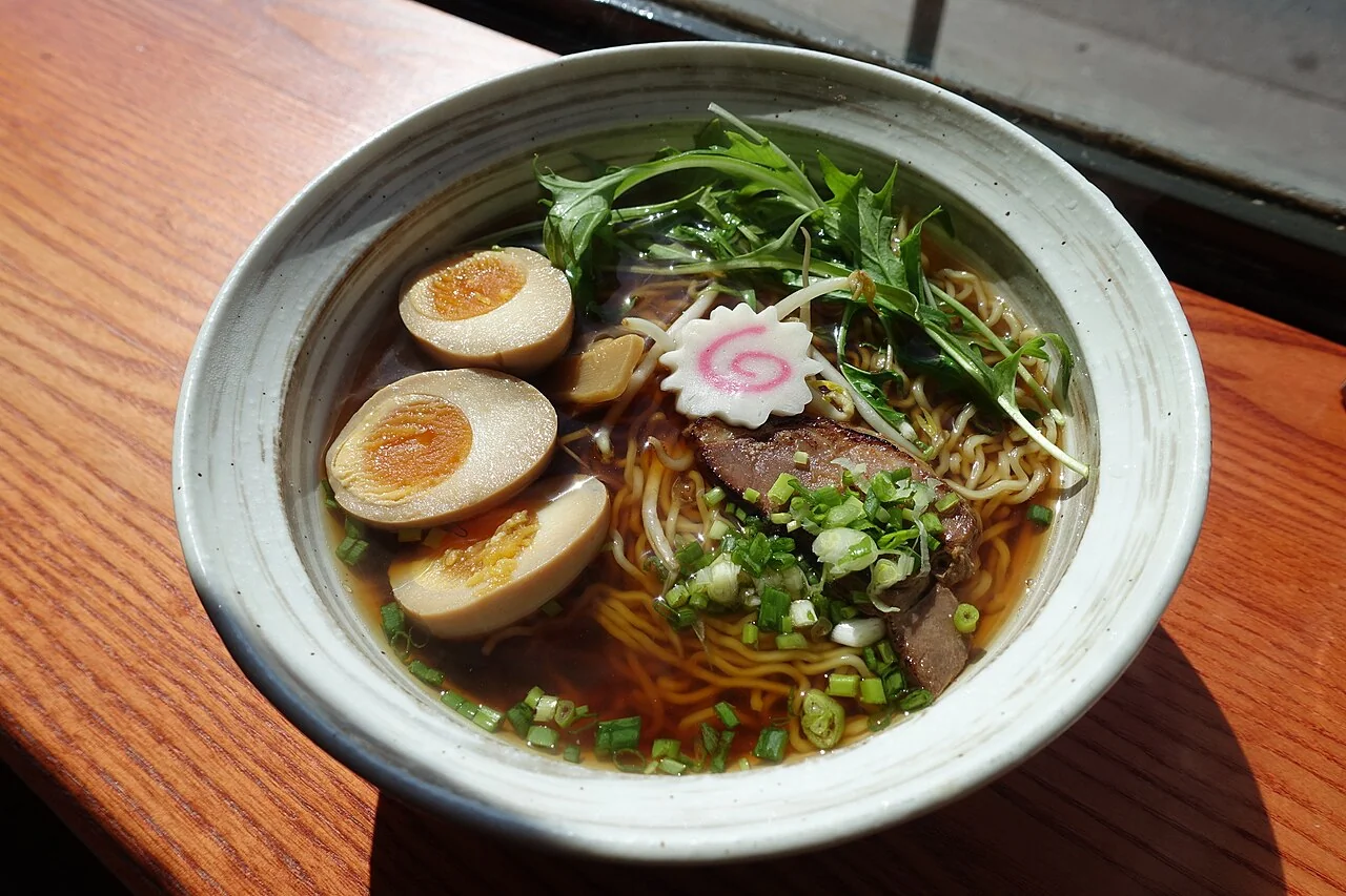 Shoyu ramen with amber broth, sliced pork, egg and greens.